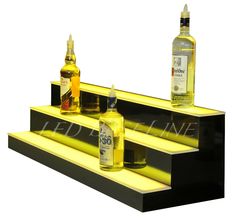 three bottles of alcohol sitting on top of some steps in front of a white background