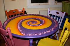 a table and chairs with an artistic design painted on the top in purple, yellow and pink