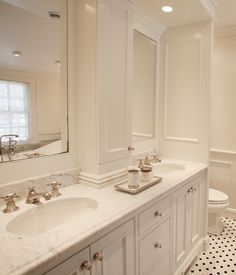 a white bathroom with black and white flooring, two sinks and a mirror on the wall