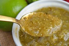 a spoon with some food in it next to limes and other fruit on the table