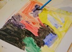 a child's painting is being made with colored paper and watercolors on the table