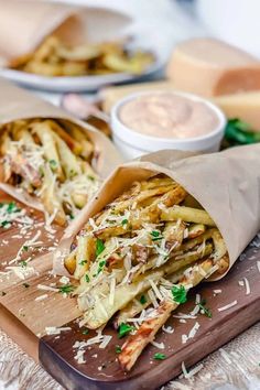 two pita sandwiches on a cutting board with cheese and parmesan dips