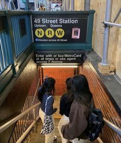 two girls are walking down the stairs at the subway station