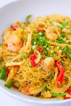 a white bowl filled with noodles, shrimp and veggies on top of it