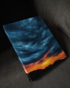 a book sitting on top of a couch next to a black chair with a blue sky in the background