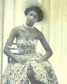 an old black and white photo of a woman in a dress sitting on a chair