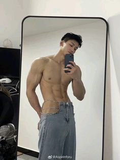 a shirtless man taking a selfie in front of a mirror with his cell phone