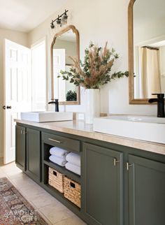 a bathroom with green cabinets and a white sink under a large mirror on the wall