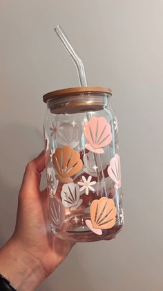 a hand holding a mason jar with flowers on it