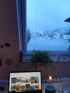 a laptop computer sitting on top of a wooden desk next to a cup and candle