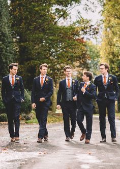 a group of young men in suits walking down a road next to trees and bushes