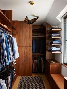 a walk in closet filled with clothes next to a window and a rug on the floor