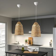 two pendant lights hanging over a kitchen island in a modern style home with grey cabinets and stainless steel appliances