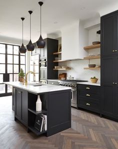 a large kitchen with black cabinets and white counter tops, an island in the middle