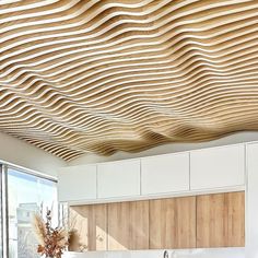 a kitchen with white cabinets and wooden ceilinging that has wavy lines on the ceiling