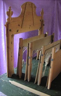 several pieces of wood are stacked on top of each other in front of a purple wall