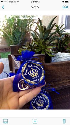 someone is holding two blue and gold badges in front of some potted greenery