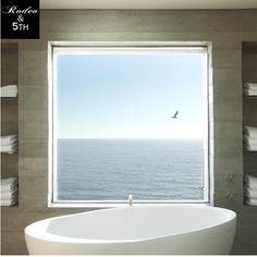 a large white bath tub sitting in front of a window next to a bathroom sink