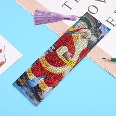 the beaded bookmark is decorated with an image of santa claus and other holiday decorations