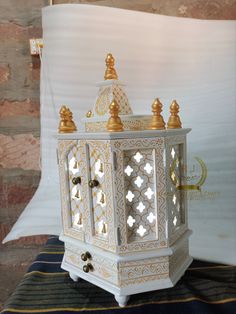 an ornate white and gold candle holder sits on a striped blanket in front of a brick wall