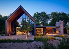 a modern house with large glass windows and wooden roof