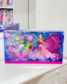 barbie the fairy princess doll in its box on a desk with other toys behind it