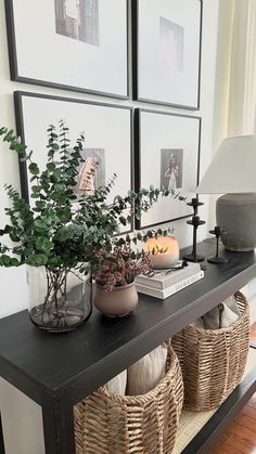 a shelf with baskets and plants on it in front of two framed pictures above them