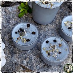 four cement pots with plants growing out of them on top of a stone surface next to a potted plant