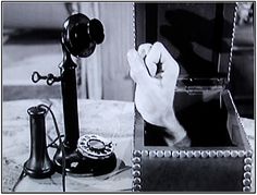 a black and white photo of an old fashioned phone with a hand holding the receiver