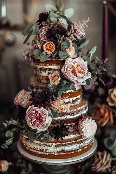 a wedding cake with flowers and greenery on top