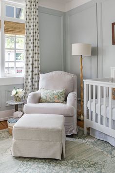 a baby's room with a white chair and foot stool