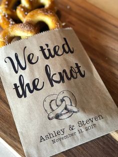 some pretzels sitting on top of a wooden table next to a bag with the words we tied the knot