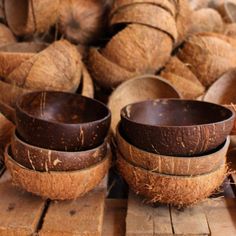 coconuts are stacked on top of each other in wooden bowls, with the tops peeled off