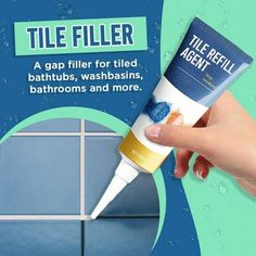 a hand holding a tube of tile filler on top of a blue tiled wall