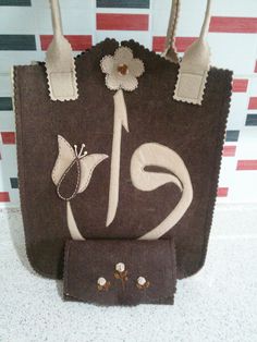 a brown purse with white flowers on the front and two handles, sitting on top of a counter