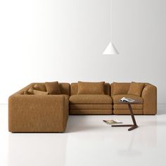 a brown sectional couch sitting on top of a white floor next to a coffee table