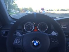 the dashboard of a bmw car on a road with other cars in the distance behind it