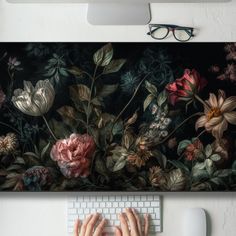 a person typing on a keyboard in front of a flowered painting with their hands