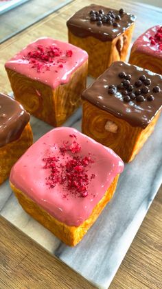 four square pastries with pink frosting and chocolate sprinkles on top