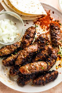 a plate with some meat and other food items on top of it next to pita bread