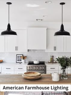 a kitchen with white cabinets and black pendant lights over the island in front of an oven