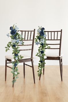 two chairs decorated with blue flowers and greenery