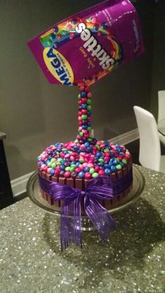 a birthday cake with candy on top and a purple wrapper sticking out of it