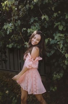 a woman standing in front of a tree smiling