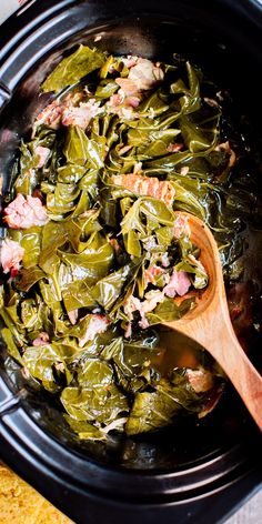 cooked collard greens in a crock pot with a wooden spoon on the side