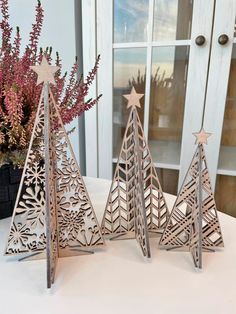 three wooden christmas trees sitting on top of a table next to a potted plant