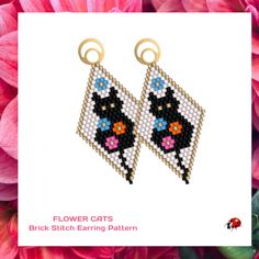 a pair of black and white cat earrings with pink flowers in the background, on a card