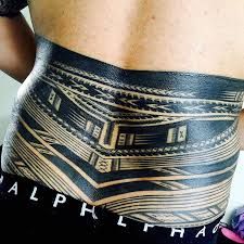 the back of a man's stomach with an intricate tattoo design on his side