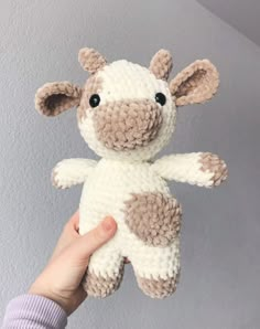 a hand holding a small stuffed animal that looks like a giraffe or cow