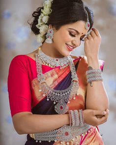 a woman in a sari is smiling and holding her hand to her ear while looking down